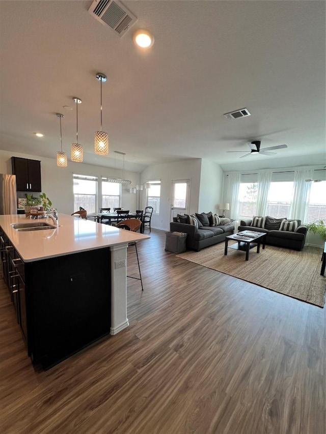 kitchen featuring dark wood finished floors, light countertops, visible vents, open floor plan, and a sink