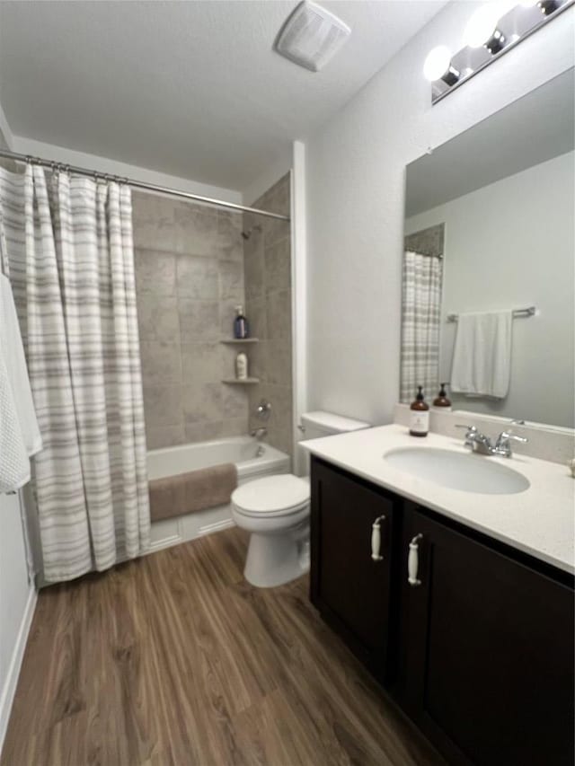 full bath with visible vents, toilet, wood finished floors, shower / bathtub combination with curtain, and vanity