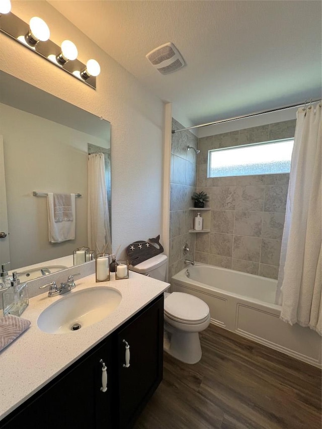 bathroom featuring shower / tub combo, visible vents, toilet, wood finished floors, and vanity