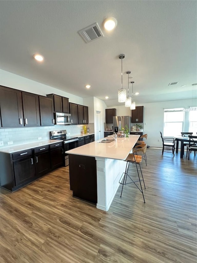 kitchen featuring visible vents, dark wood finished floors, stainless steel appliances, light countertops, and backsplash