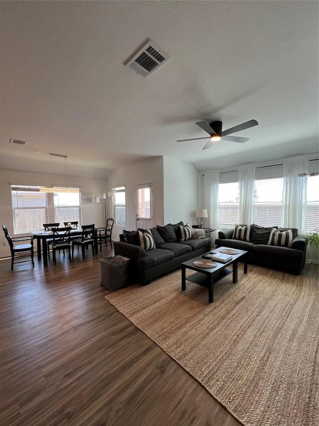 living room with dark wood-style floors, a wealth of natural light, and visible vents