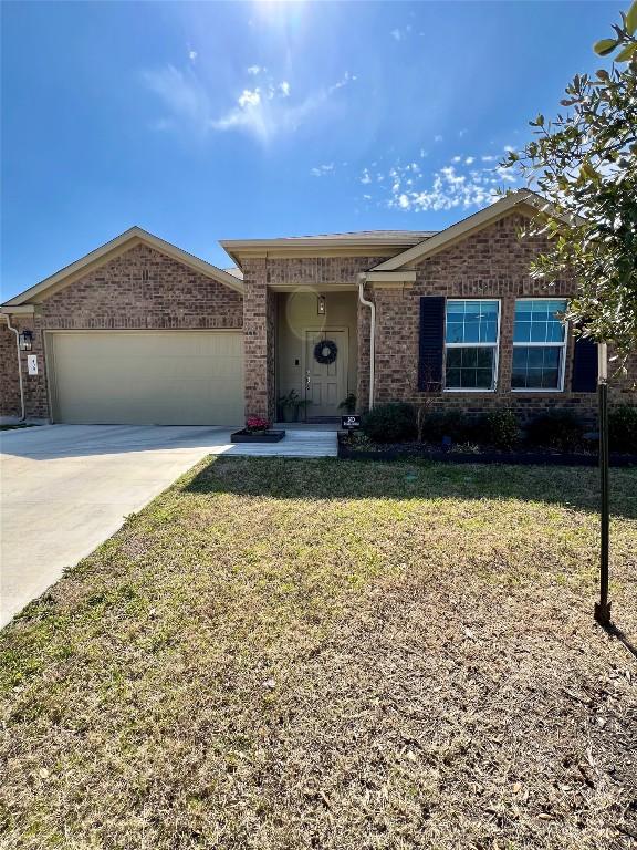 single story home featuring a front lawn, concrete driveway, brick siding, and a garage