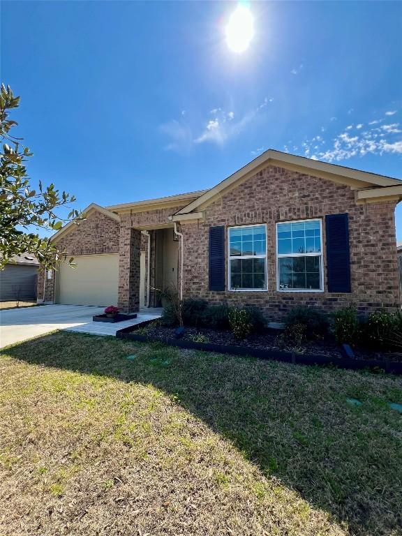 ranch-style house with a garage, concrete driveway, brick siding, and a front yard