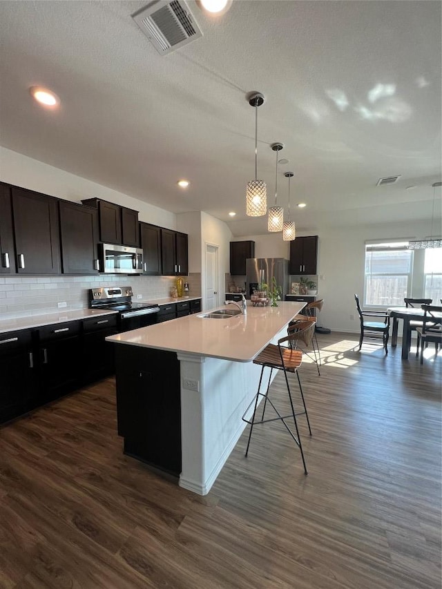 kitchen with stainless steel appliances, a large island with sink, a sink, and visible vents