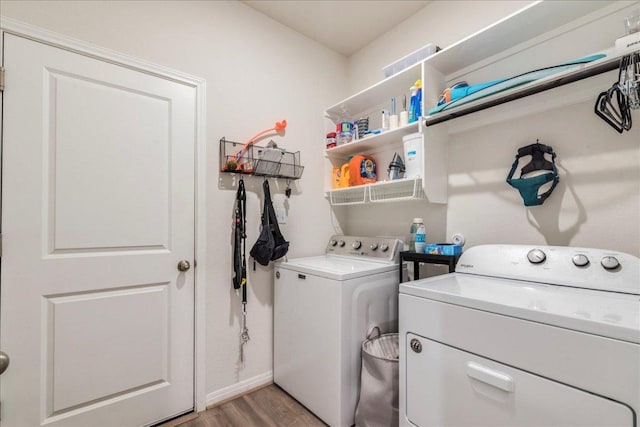 washroom with light wood-type flooring, laundry area, baseboards, and washing machine and clothes dryer