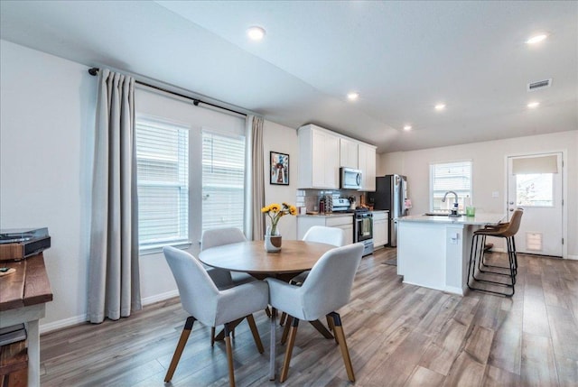 dining space featuring lofted ceiling, recessed lighting, visible vents, light wood-style floors, and baseboards