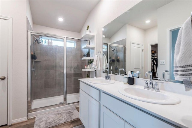 full bathroom with double vanity, a sink, a walk in closet, and a shower stall