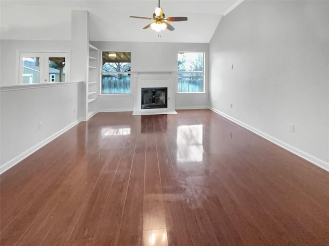 unfurnished living room with built in shelves, dark wood finished floors, a fireplace with flush hearth, vaulted ceiling, and baseboards