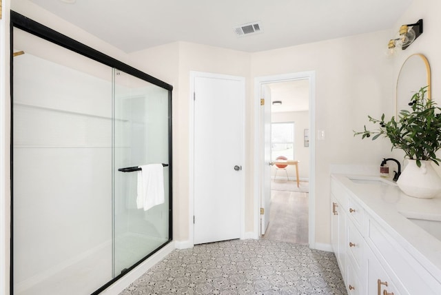 full bathroom with double vanity, a stall shower, visible vents, and a sink