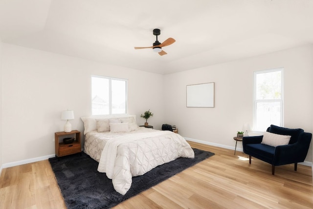 bedroom with baseboards, multiple windows, and light wood finished floors