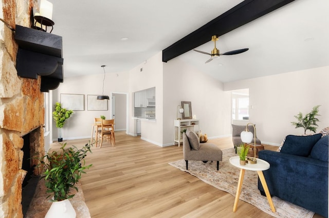 living room featuring vaulted ceiling with beams, ceiling fan, light wood-type flooring, and baseboards