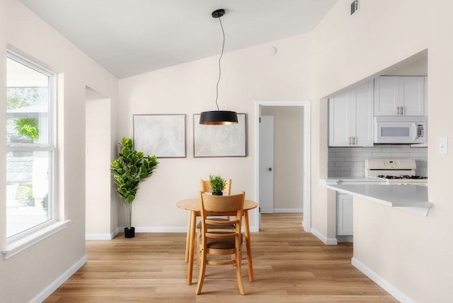 kitchen with white microwave, visible vents, light countertops, decorative backsplash, and gas range oven