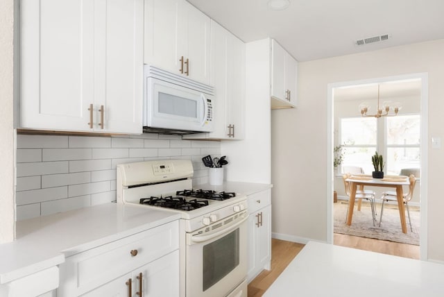 kitchen featuring light countertops, white appliances, white cabinets, and decorative backsplash