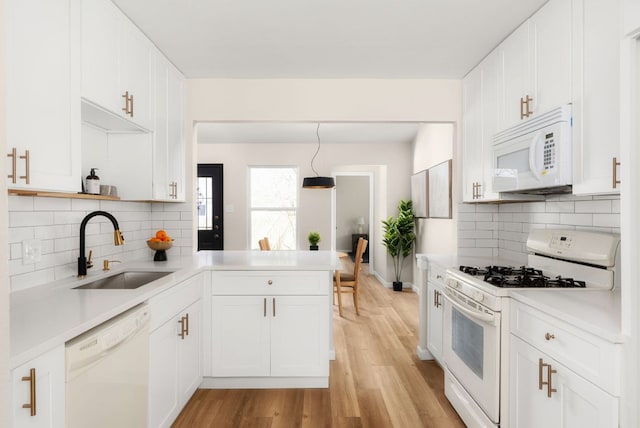 kitchen featuring light countertops, white cabinetry, a sink, white appliances, and a peninsula