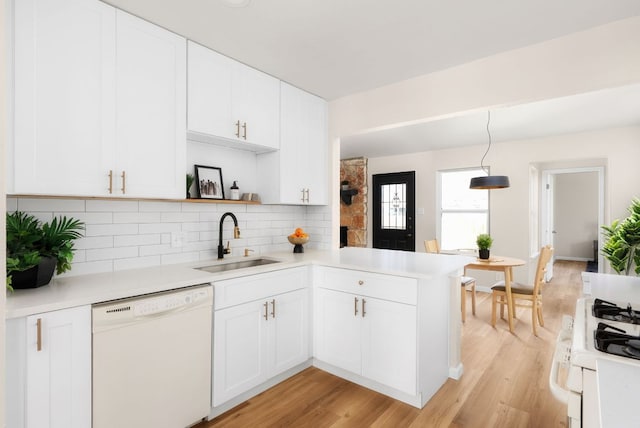 kitchen with a peninsula, white appliances, a sink, light countertops, and open shelves