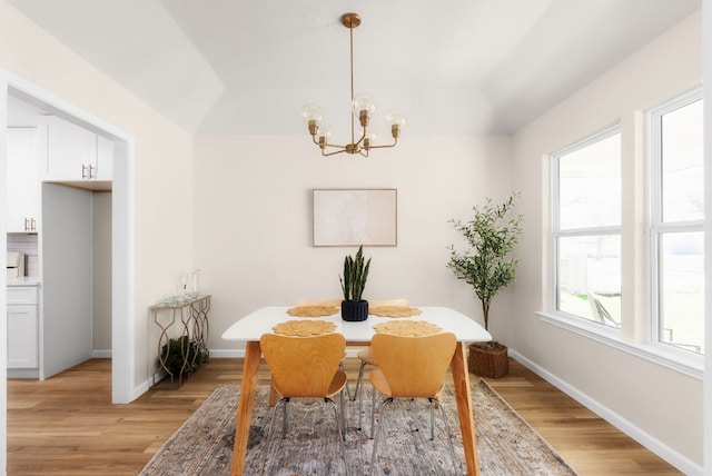 dining space featuring a chandelier, light wood-type flooring, and baseboards