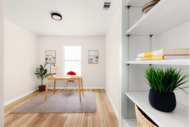 office area with light wood-style floors, visible vents, and baseboards