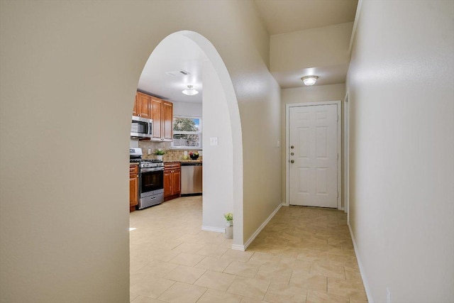 corridor with visible vents, arched walkways, and baseboards