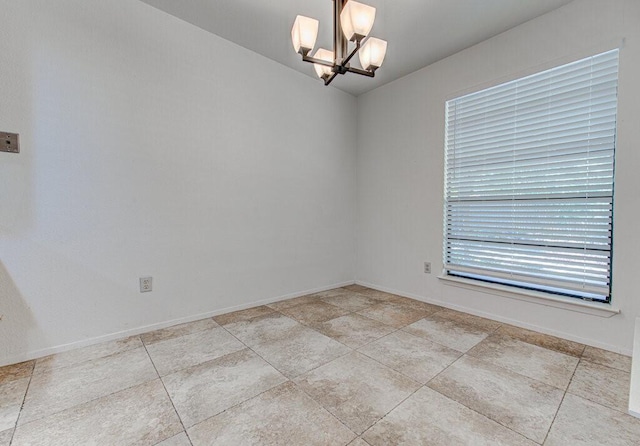 unfurnished room with baseboards and a notable chandelier