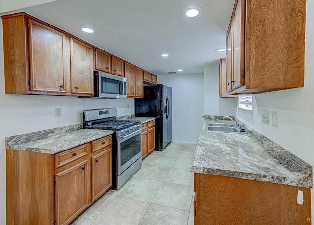 kitchen with light tile patterned floors, appliances with stainless steel finishes, brown cabinets, a sink, and recessed lighting