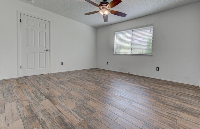 unfurnished room with ceiling fan, a textured ceiling, baseboards, and wood finished floors