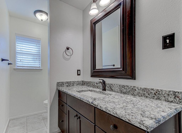 bathroom featuring baseboards, vanity, toilet, and tile patterned floors