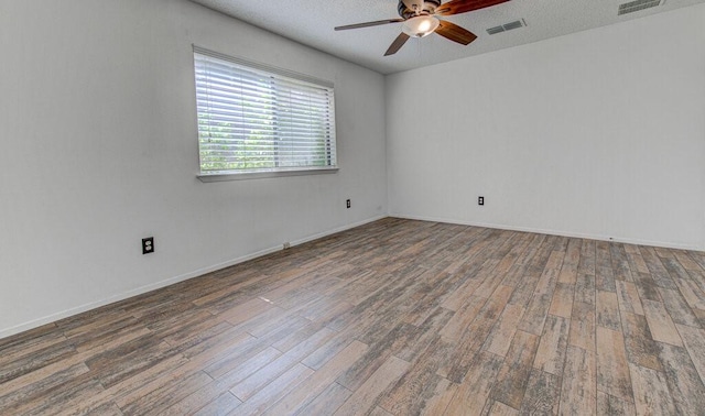 unfurnished room with a ceiling fan, visible vents, and wood finished floors