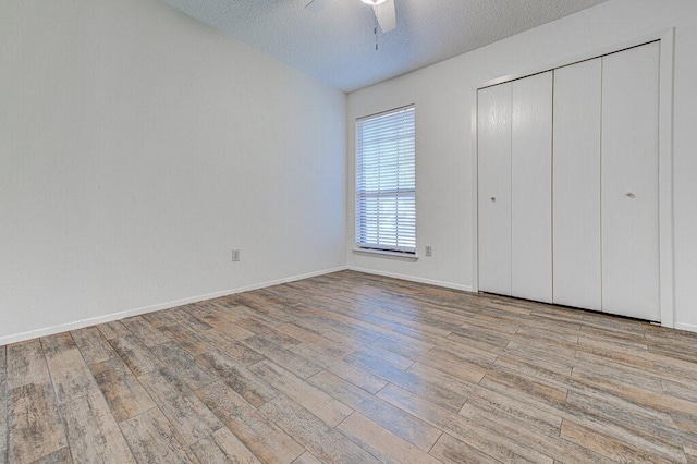 unfurnished bedroom featuring a textured ceiling, ceiling fan, wood finished floors, and baseboards