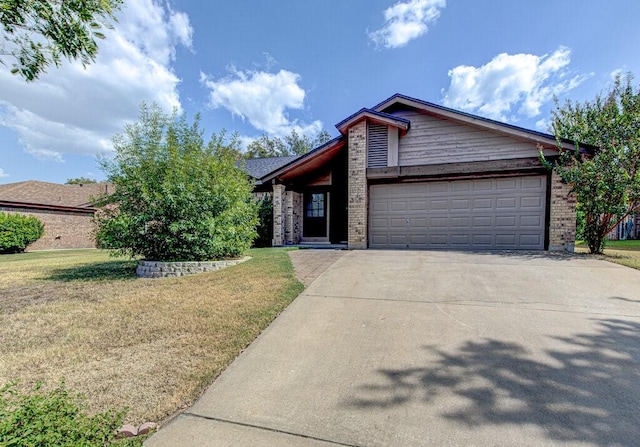 view of front facade featuring a garage, a front yard, brick siding, and driveway