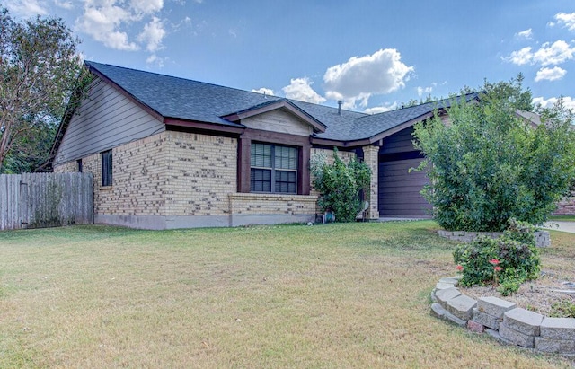 ranch-style house with a shingled roof, brick siding, fence, and a front lawn