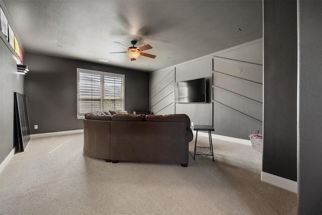 living area featuring a ceiling fan, light colored carpet, a textured ceiling, and baseboards