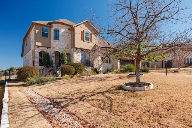 view of front facade featuring a garage, stone siding, fence, and stucco siding