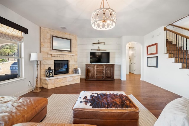 205 Agave Bloom Cv, Austin, TX 78738 - living room featuring stairs, a chandelier, wood finished floors, arched walkways, and a stone fireplace