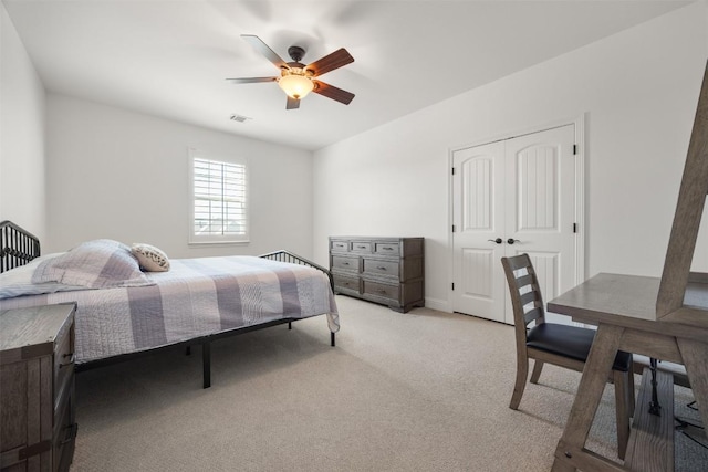 bedroom with a ceiling fan, a closet, visible vents, and light carpet