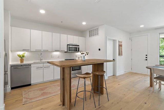 kitchen featuring wooden counters, appliances with stainless steel finishes, visible vents, and tasteful backsplash