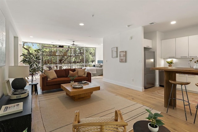 living room featuring recessed lighting, visible vents, baseboards, light wood finished floors, and a wall of windows