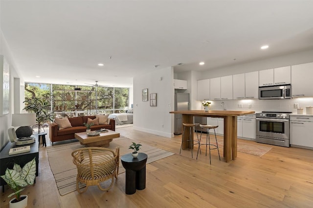 interior space featuring baseboards, light wood finished floors, a wall of windows, and recessed lighting