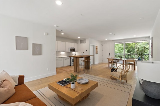 living room with light wood finished floors, visible vents, and recessed lighting