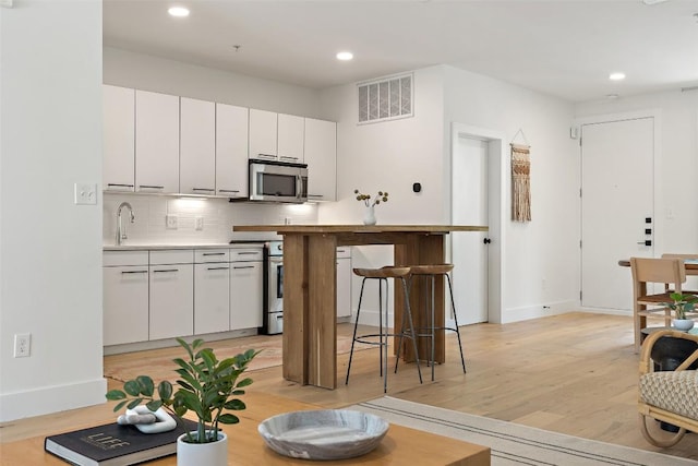 kitchen with visible vents, decorative backsplash, appliances with stainless steel finishes, light wood-style floors, and recessed lighting