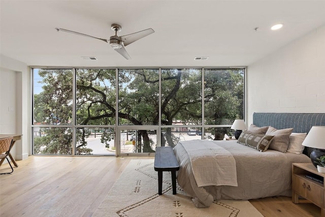 bedroom with floor to ceiling windows, ceiling fan, visible vents, and wood finished floors