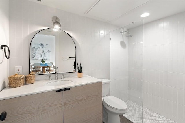 bathroom featuring vanity, walk in shower, toilet, and tile walls