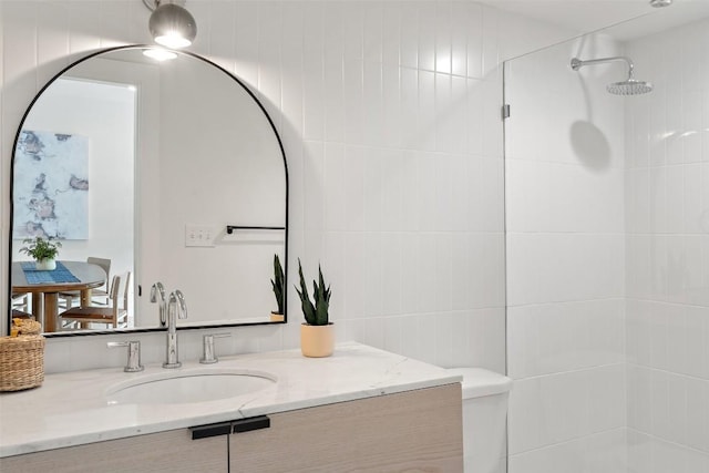 full bathroom featuring tiled shower and vanity