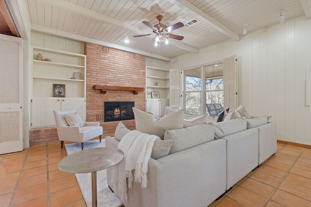 living room with light tile patterned floors, built in shelves, a fireplace, visible vents, and beam ceiling