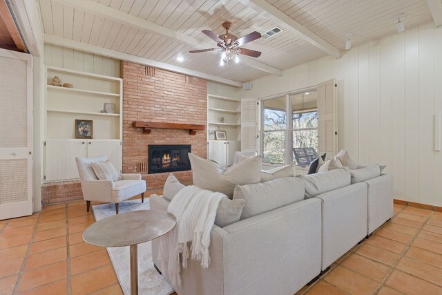 6615 La Concha Pass, Austin, TX 78749 - living room with a ceiling fan, built in features, light tile patterned floors, a fireplace, and wooden ceiling with exposed beams