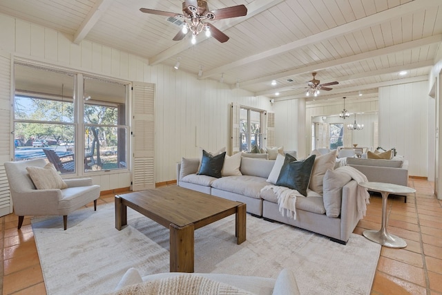 living area featuring beamed ceiling and ceiling fan with notable chandelier