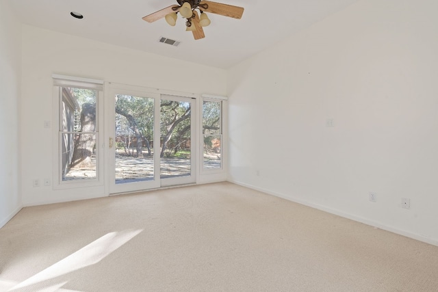 spare room with light colored carpet, visible vents, ceiling fan, and baseboards