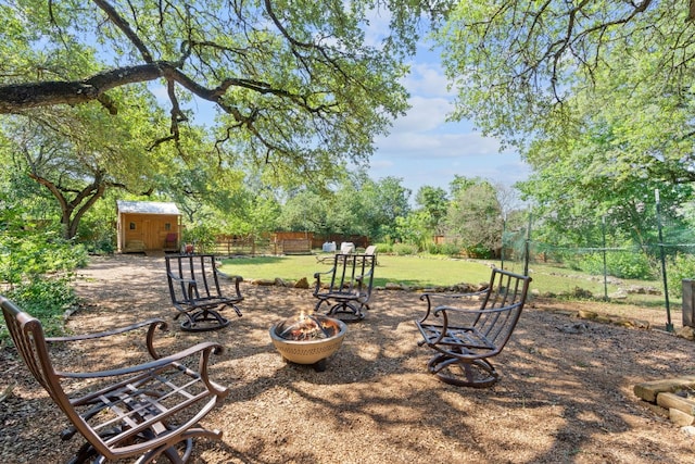 view of yard featuring a shed, an outdoor fire pit, fence, and an outbuilding