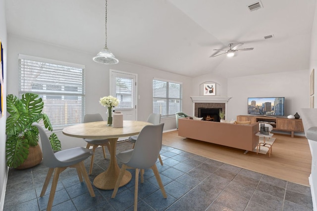 dining area with visible vents, lofted ceiling, ceiling fan, and a tile fireplace