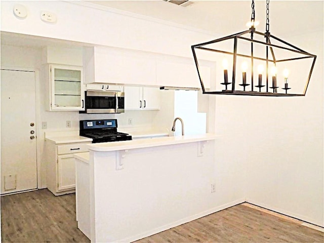 kitchen with light countertops, stainless steel microwave, wood finished floors, and gas range