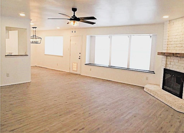 unfurnished living room featuring a ceiling fan, a fireplace, and wood finished floors